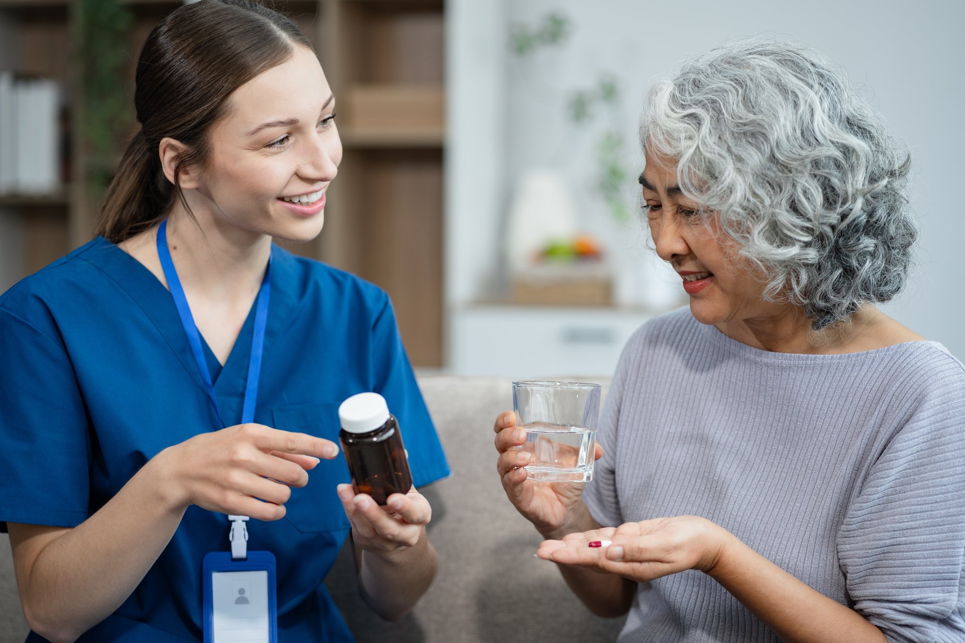 Pflegerin erklärt einer Seniorin die Medikamenteneinnahme